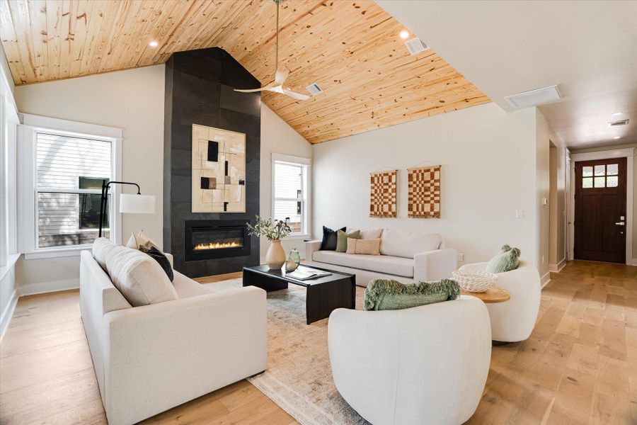 This living space features a vaulted wood plank ceiling, light wood floors, and a dark tile fireplace with an electric insert This living space features a vaulted wood plank ceiling, light wood floors, and a dark tile fireplace with an electric insert