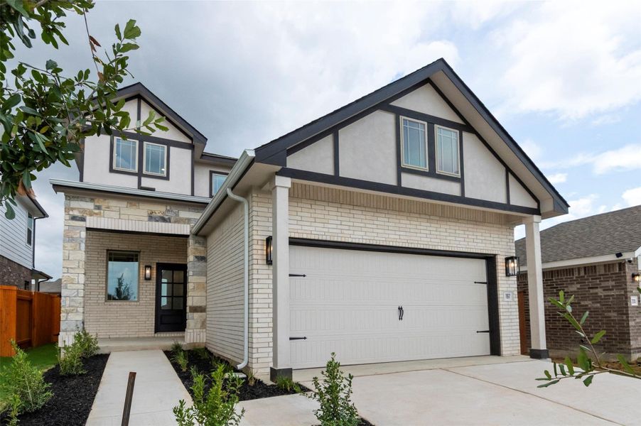 English style home featuring a garage, brick siding, driveway, and stucco siding English style home featuring a garage, brick siding, driveway, and stucco siding