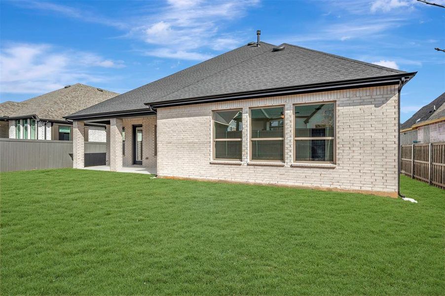 Rear view of property featuring a fenced backyard, a shingled roof, a patio area, and brick siding