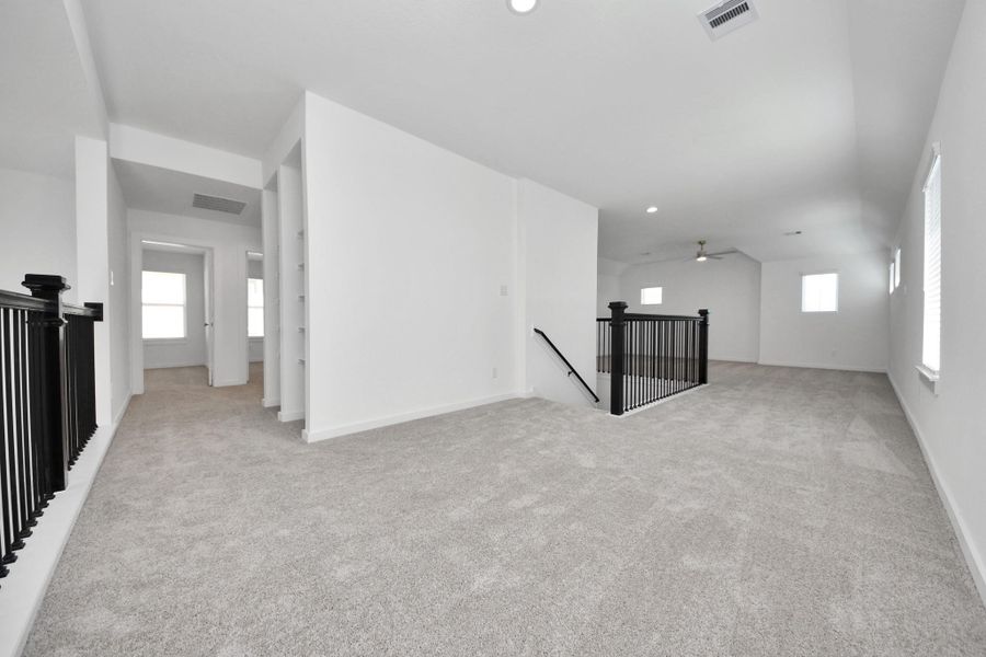 Come upstairs and relish a day of relaxation in this loft area! Ideal as an additional living space or game room, it boasts plush carpeting, high ceilings, custom paint, and windows that flood the area with abundant natural light. Sample photo of completed home with similar floor plan. Actual colors and selections may vary.