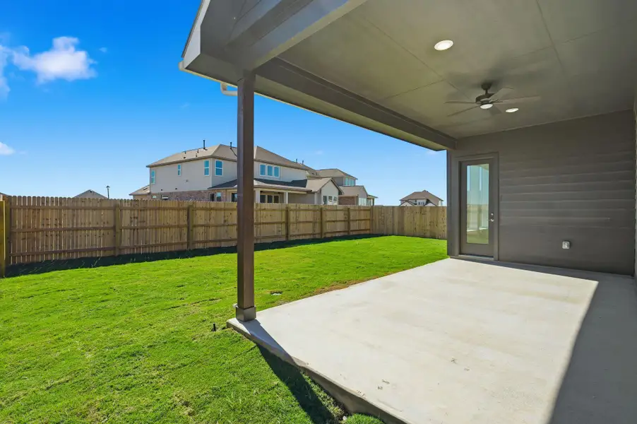 Fenced backyard with ceiling fan, a patio, and a residential view