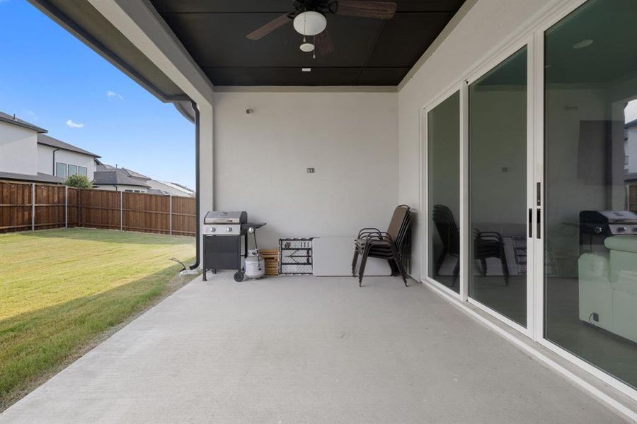 Fenced backyard with a ceiling fan, a patio, and grilling area