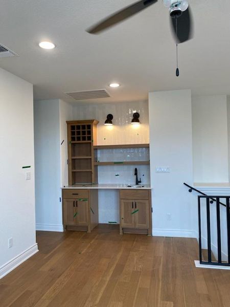 Bar featuring wood finish cabinetry, dark wood-type flooring, light countertops, recessed lighting, and a ceiling fan