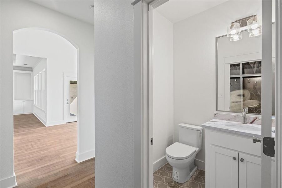 Powder room featuring a white single-sink vanity with a patterned countertop, a rectangular mirror, and an overhead light fixture