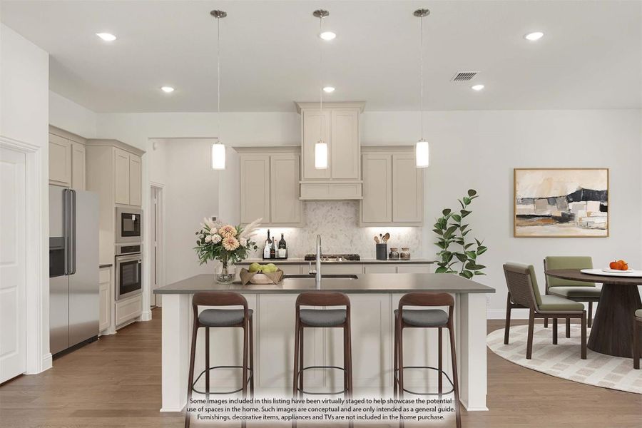 Kitchen with cream cabinets, large island with three bar stools, pendant lights, and stainless steel appliances