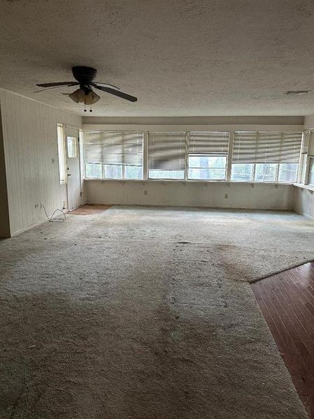 Empty room featuring a textured ceiling, wood finished floors, and a ceiling fan