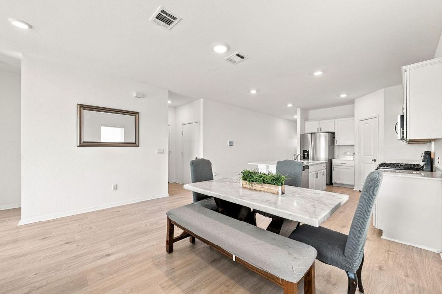 Gleaming wood-look floors anchor this airy, open-concept dining area adjacent to the modern kitchen.