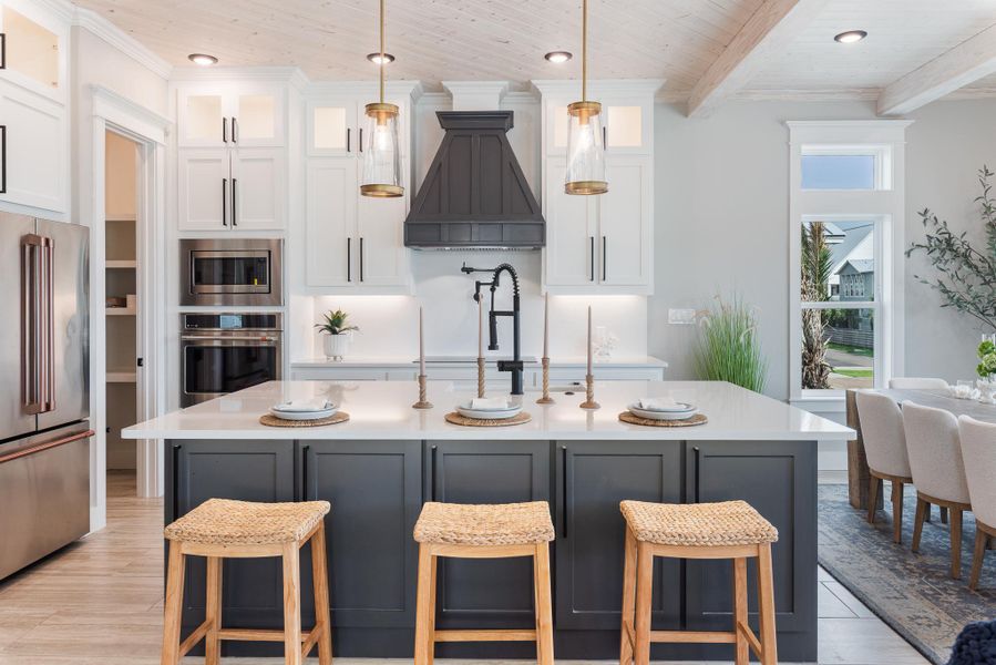 Kitchen featuring appliances with stainless steel finishes, custom range hood, white cabinets, a wooden ceiling with exposed beams, and glass insert cabinets Kitchen featuring appliances with stainless steel finishes, custom range hood, white cabinets, a wooden ceiling with exposed beams, and glass insert cabinets