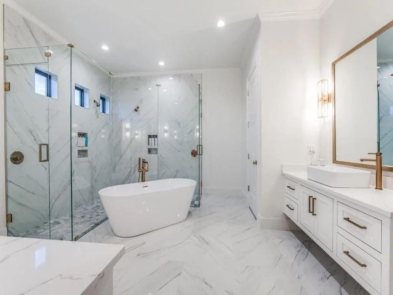 Full bathroom with recessed lighting, a freestanding tub, vanity, a marble finish shower, and light marble finish floors