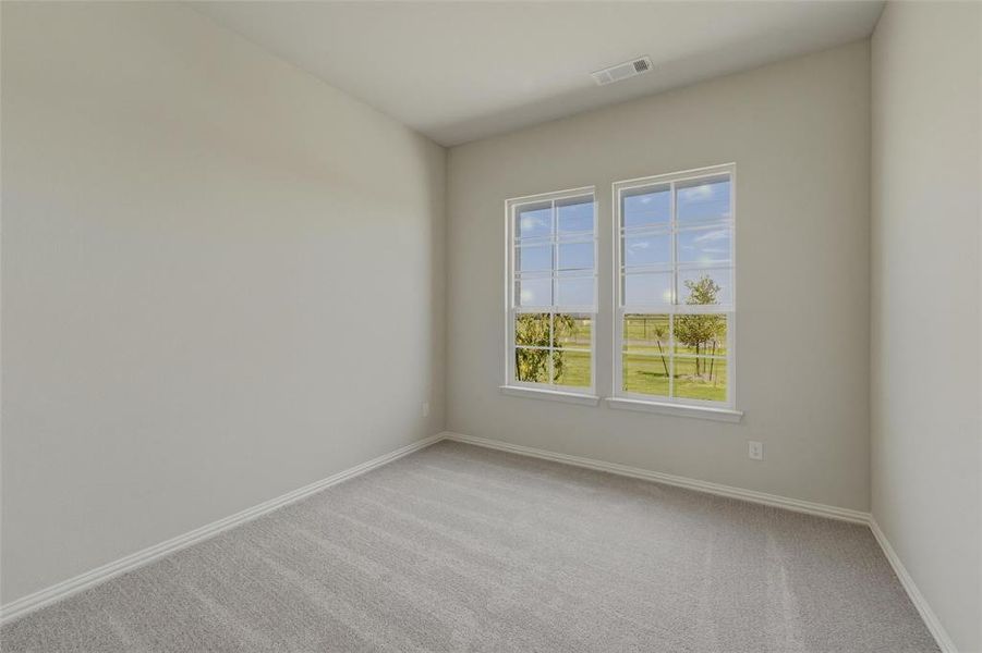 Bright interior space featuring two large windows with white trim, light gray carpeting, and neutral-toned walls Bright interior space featuring two large windows with white trim, light gray carpeting, and neutral-toned walls