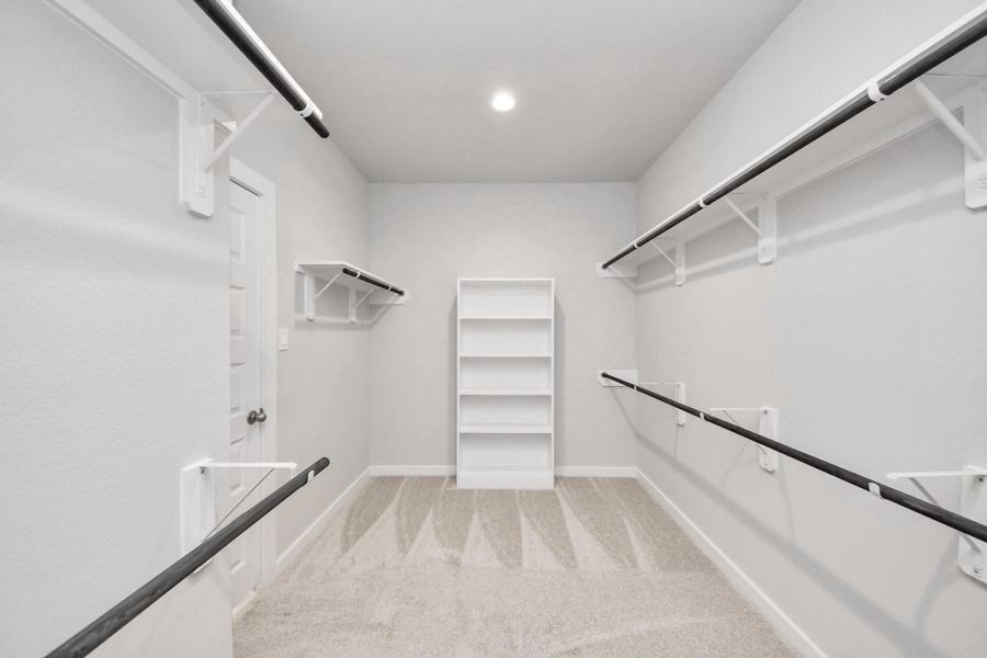 Walk-in closet that epitomizes luxury and practicality. This generously sized space features built-in shelving, offering abundant room for impeccable organization. High ceilings and recessed lighting create a bright and welcoming ambiance. Sample photo of completed home with similar floor plan. Actual colors and selections may vary. Walk-in closet that epitomizes luxury and practicality. This generously sized space features built-in shelving, offering abundant room for impeccable organization. High ceilings and recessed lighting create a bright and welcoming ambiance. Sample photo of completed home with similar floor plan. Actual colors and selections may vary.