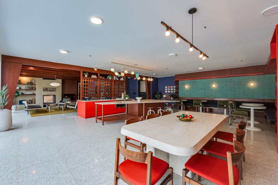 This inviting common area features a spacious layout with terrazzo flooring, a large island with seating, and a dining table with chairs