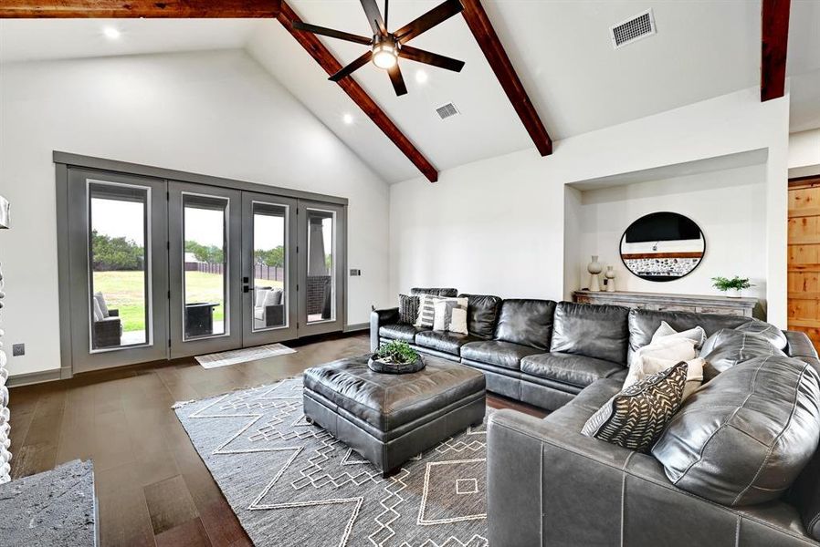 Living area with beam ceiling, high vaulted ceiling, french doors, wood finished floors, and recessed lighting