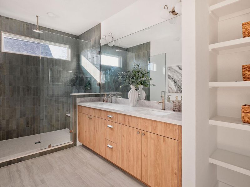 Full bath with double vanity, built in shelves, and a shower stall
