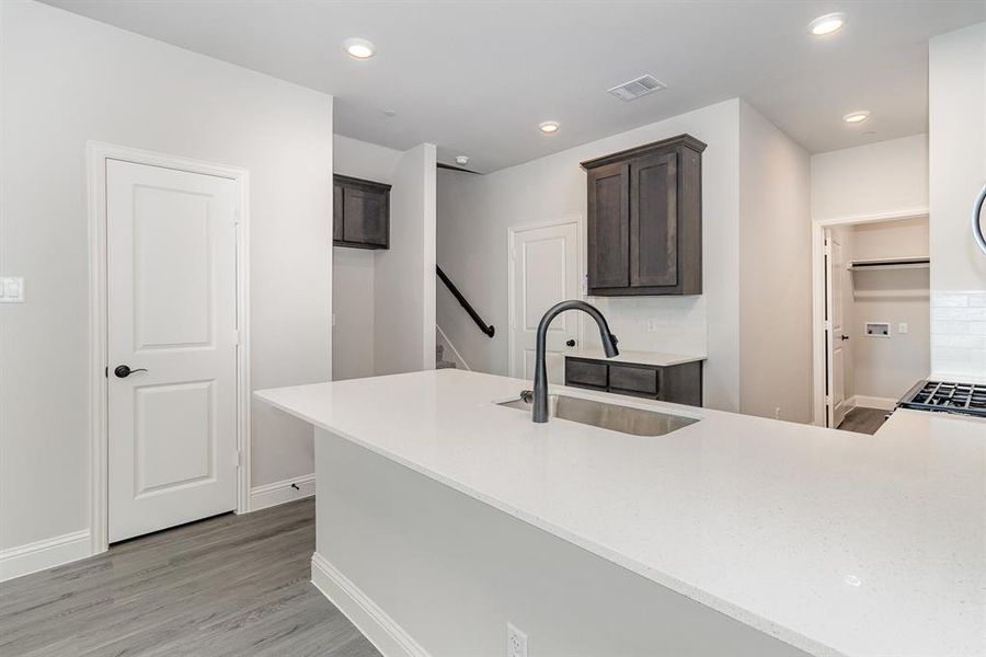 Kitchen with sink, light wood-type flooring, backsplash, and dark brown cabinets