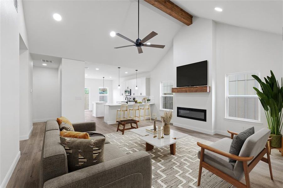 Living room featuring beam ceiling, light hardwood / wood-style floors, a large fireplace, high vaulted ceiling, and ceiling fan