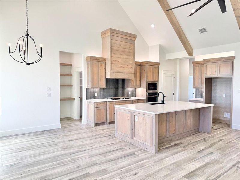 Kitchen featuring a kitchen island with sink, oven, visible vents, built in microwave, and cooktop