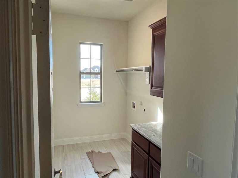 Laundry area with cabinets, hookup for a washing machine, and electric dryer hookup