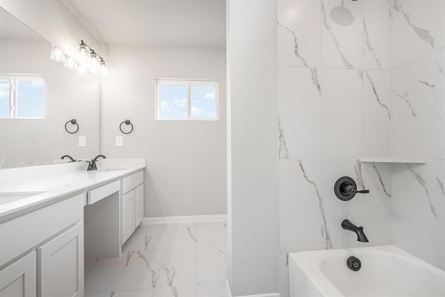 Bathroom with double vanity, light marble finish floors, and bathtub / shower combination