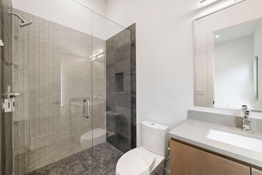 Modern bathroom featuring a glass-enclosed shower with a rain shower head and a tiled shower pan