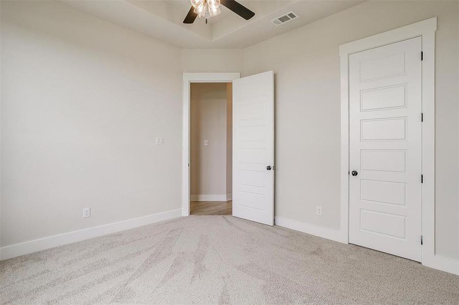 Unfurnished bedroom with light colored carpet and ceiling fan