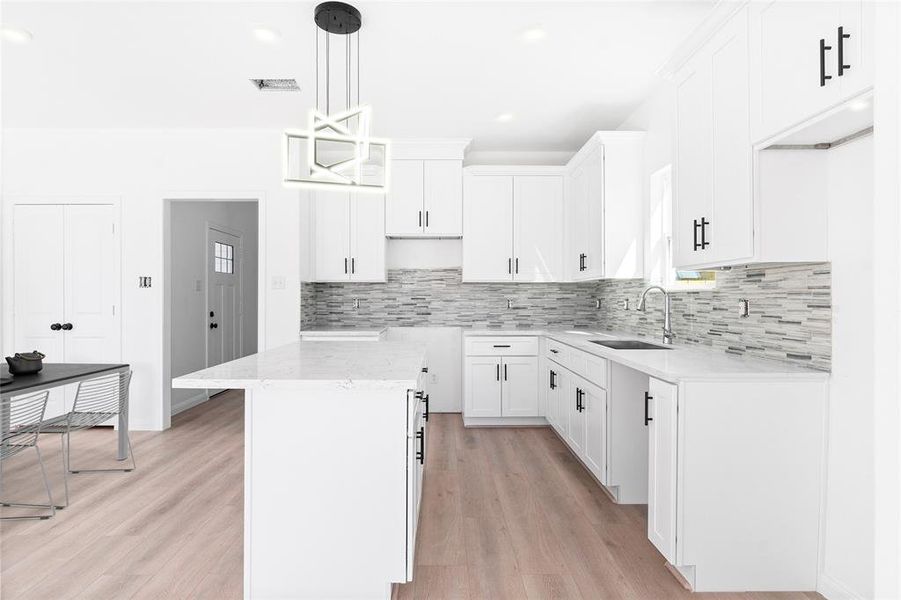 The kitchen shines with quartz countertops, a premium backsplash, and a spacious island perfect for cooking or gathering. (Photo may be enhanced and may include virtual staging)