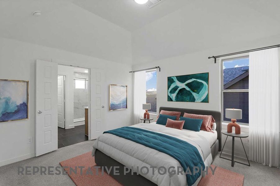 A cozy primary bedroom features sunlit windows and elegant French doors that open into the primary bathroom, creating a private and relaxing retreat.