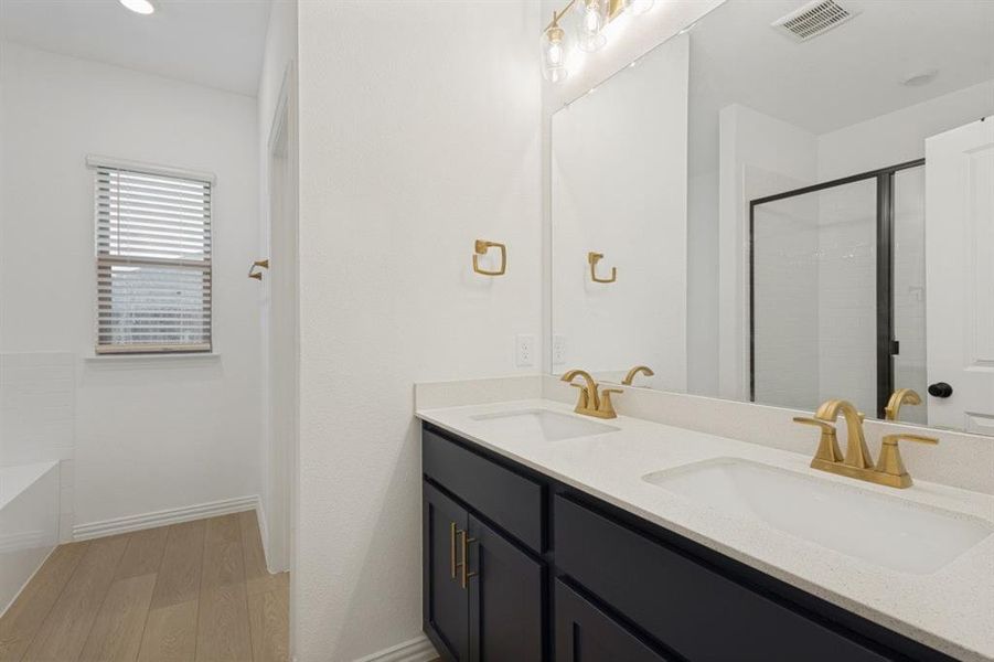 Bathroom featuring a double vanity with dark cabinetry, integrated sinks, and gold-finish faucets