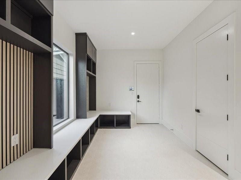 A spacious mudroom with tailored built-ins continues the home’s modern aesthetic, offering generous storage and effortless style.