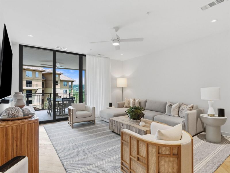 Living space featuring light wood-finish flooring and a spacious balcony with black metal railings Living space featuring light wood-finish flooring and a spacious balcony with black metal railings