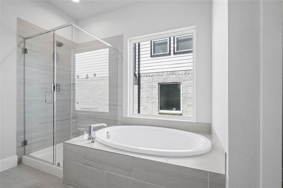 This master bathroom is definitely move-in ready! Featuring dark framed walk-in shower with tile surround, separate garden tub for soaking after a long day with custom tile detailing, high ceilings, custom paint, sleek and dark modern finishes!