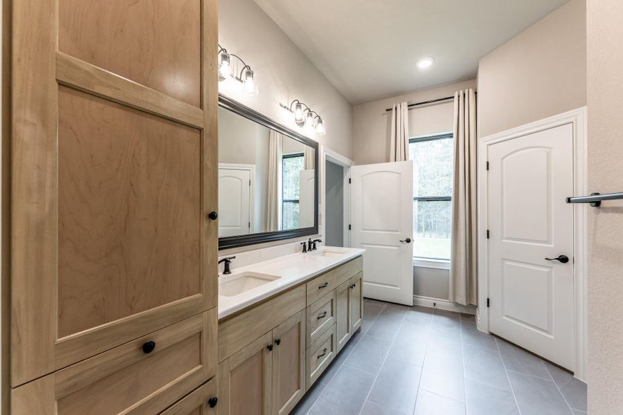 Complimentary colored cabinetry, dual vanity, wide doors and lovely window