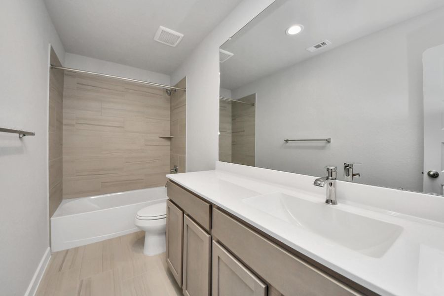 Secondary bath features tile flooring, bath/shower combo with tile surround, light stainedwood cabinets, beautiful light countertop. Sample photo of completed home with similar floor plan. Actual colors and selections may vary. Secondary bath features tile flooring, bath/shower combo with tile surround, light stainedwood cabinets, beautiful light countertop. Sample photo of completed home with similar floor plan. Actual colors and selections may vary.