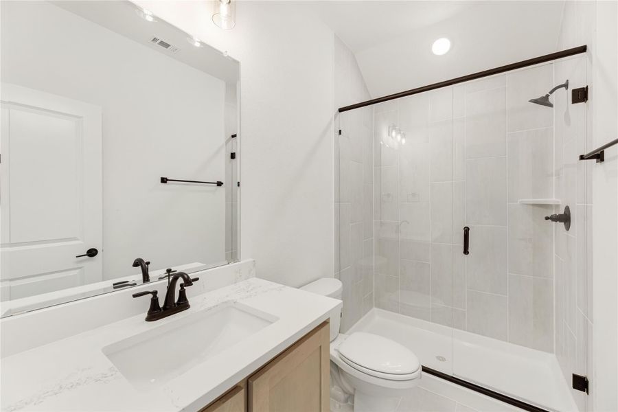 Bathroom with quartz vanity, glass-enclosed tile shower, and dark bronze fixtures Bathroom with quartz vanity, glass-enclosed tile shower, and dark bronze fixtures