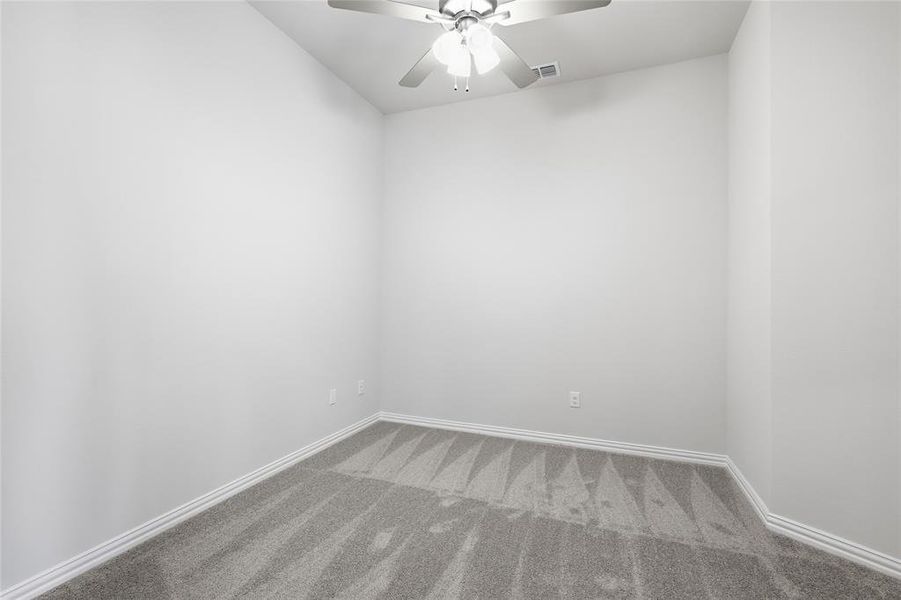 Carpeted empty room with a ceiling fan and baseboards Carpeted empty room with a ceiling fan and baseboards