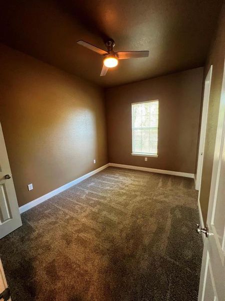 Unfurnished bedroom featuring dark carpet and ceiling fan Unfurnished bedroom featuring dark carpet and ceiling fan