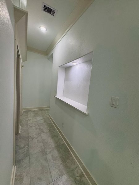 Hallway to powder room, utility room, garage access and Primary suite