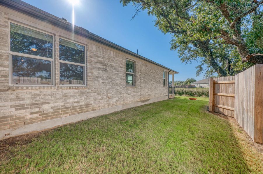 A classic brick exterior sits adjacent to a private grassy lawn enclosed by wood fencing.