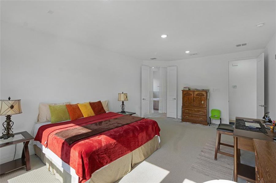 Spacious bedroom featuring light-colored carpeting, recessed lighting, and white walls