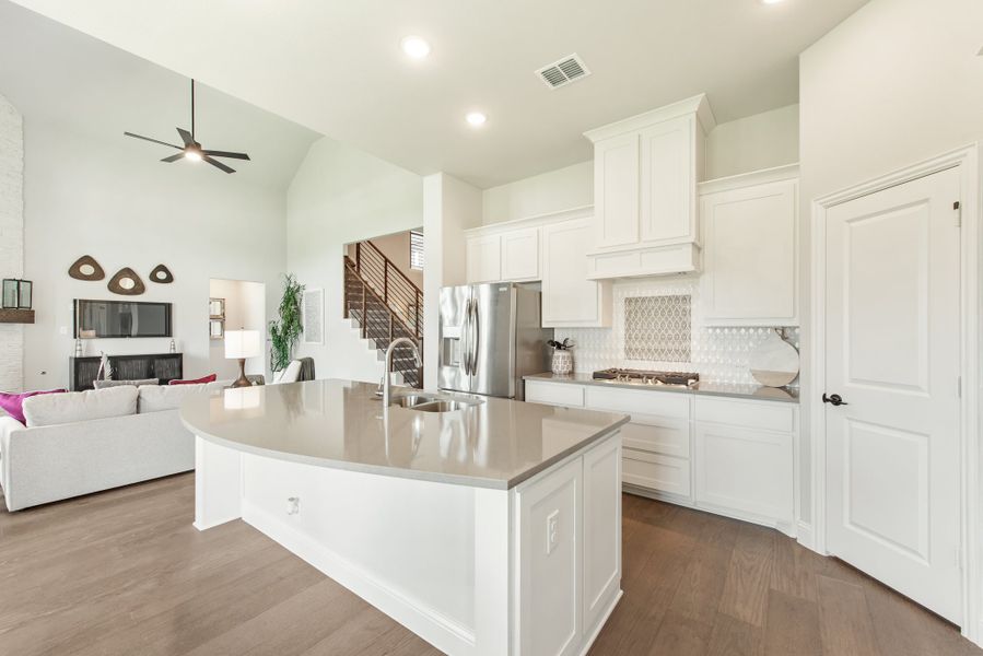 Open-concept kitchen with white cabinets, center island, and stainless steel appliances, open to living room with high ceilings. Open-concept kitchen with white cabinets, center island, and stainless steel appliances, open to living room with high ceilings.
