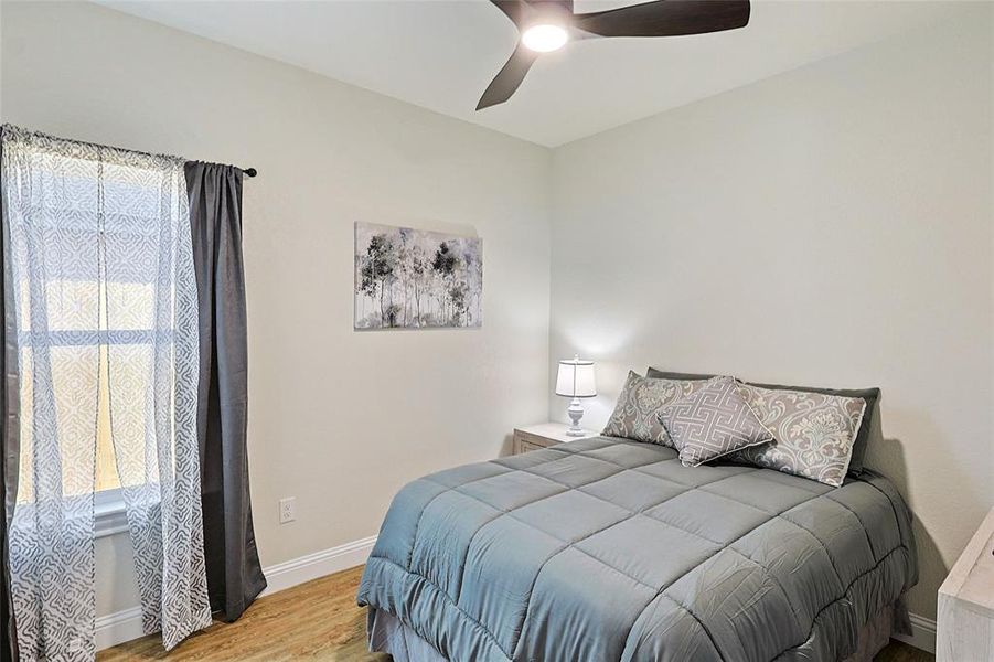 Recessed window with white trim, wood-finish flooring, white baseboards, and a contemporary ceiling fan with integrated lighting