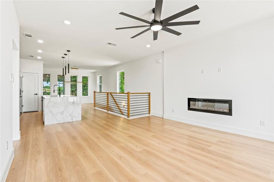 Unfurnished living room featuring a glass covered fireplace, recessed lighting, light wood-style flooring, and a ceiling fan