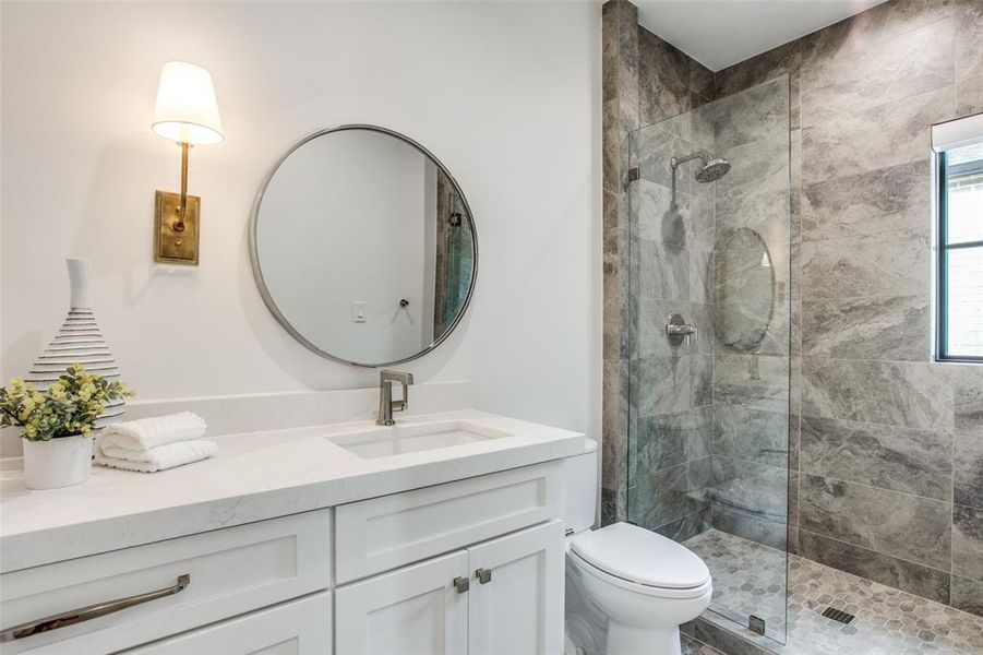 Bathroom with a tile shower, vanity, and toilet