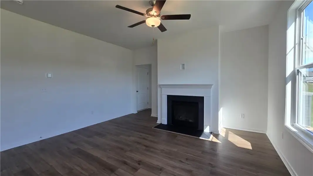 Rich wood floors and a classic fireplace mantel an