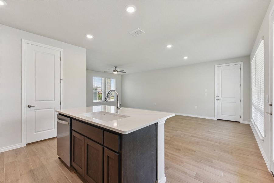 Kitchen with recessed lighting, dark brown cabinetry, open floor plan, light wood finished floors, and a center island with sink Kitchen with recessed lighting, dark brown cabinetry, open floor plan, light wood finished floors, and a center island with sink