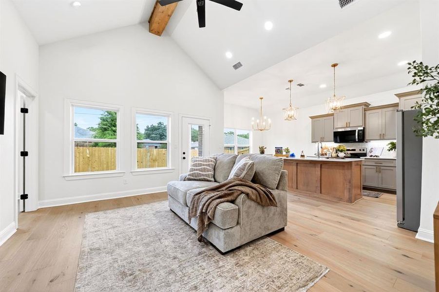 Vaulted ceiling with an exposed wood beam, wood-finish flooring, and white walls