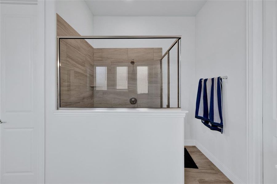 Bathroom with light wood finished floors and tiled shower
