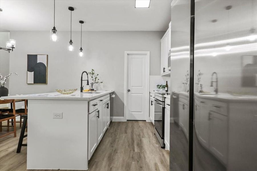 Kitchen with a kitchen breakfast bar, sink, light hardwood / wood-style flooring, white cabinetry, and hanging light fixtures