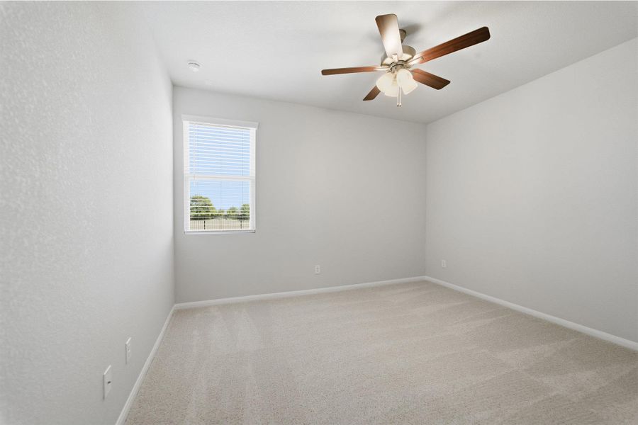 Empty room with light colored carpet and a ceiling fan