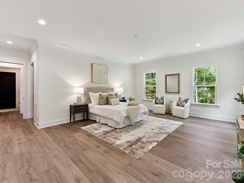 Spacious primary suite featuring a serene sitting area, large windows with wooded views, and plenty of room to relax and unwind.